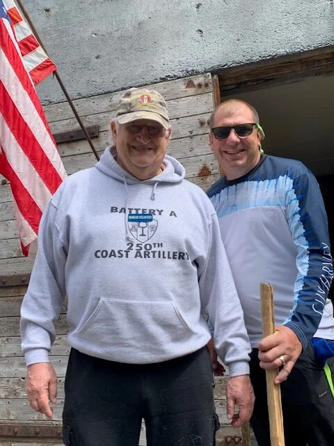 Two men standing next to each other in front of a flag.