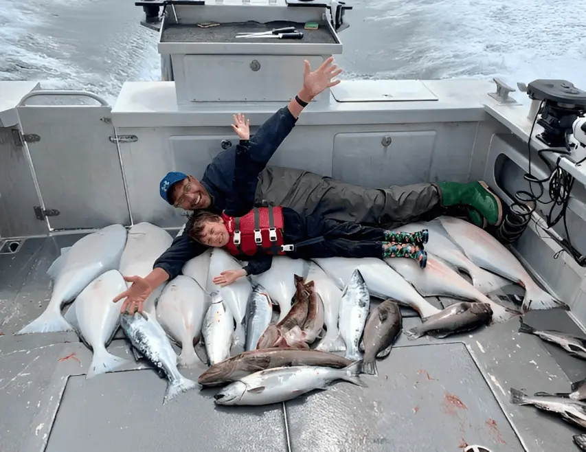 A man and child on the deck of a boat with fish.