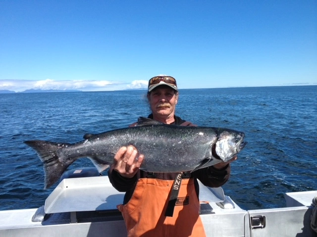 A man holding a large fish on top of a boat.