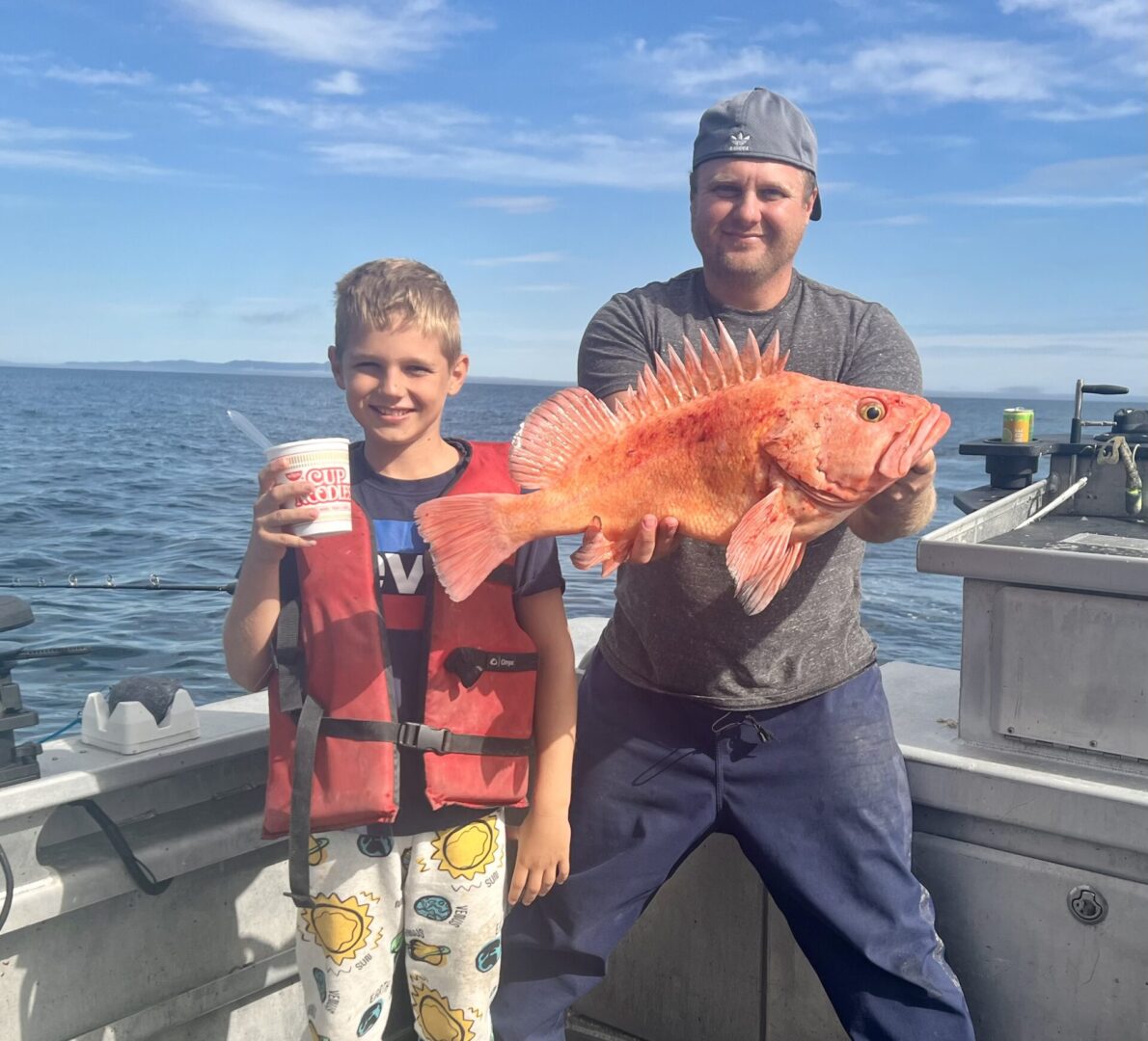 A man and a boy holding a big orange fish